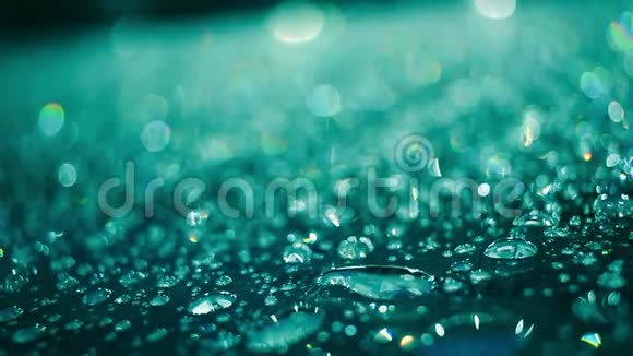雨滴在玻璃表面呈水蓝色玻璃上液滴的宏观视频的预览图