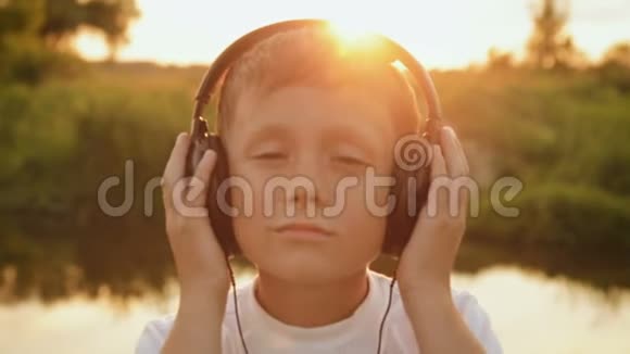 在夕阳下男孩通过耳机听音乐视频的预览图