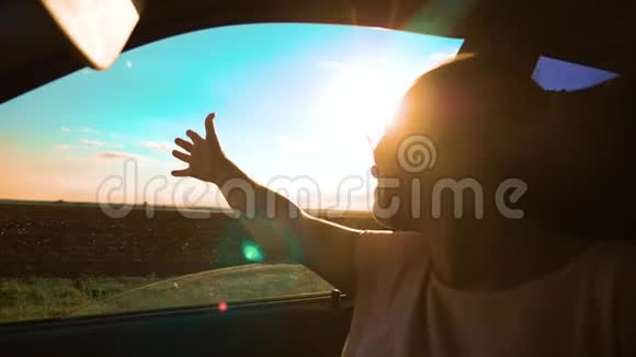 青少年在汽车慢动作视频中挥动她的手年轻快乐的小女孩开着一辆车手伸出来视频的预览图