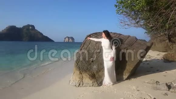 新娘靠在岩石上看着海滩视频的预览图