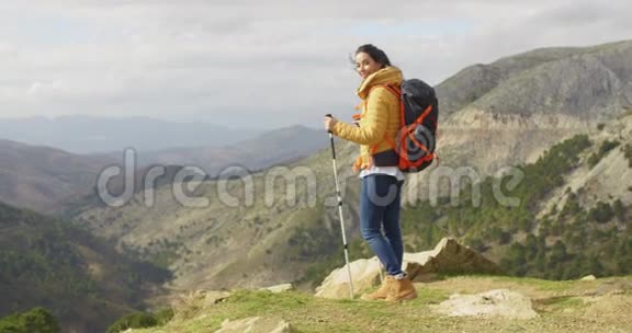 年轻女子徒步旅行者站在俯瞰山谷视频的预览图