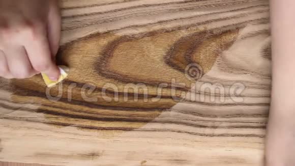 处理木材用浸渍法进行保护女性用海绵在木板上涂亚麻籽油视频的预览图