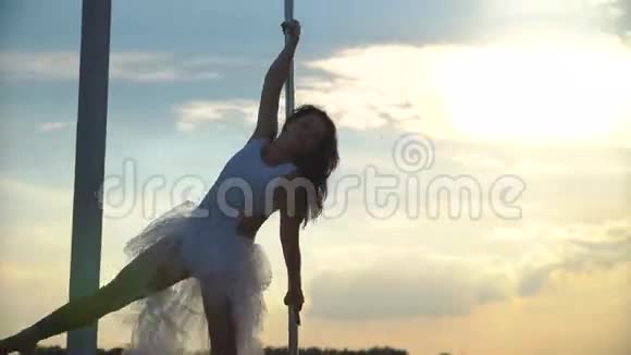 迷人的女歌手在夕阳下在天际线上的便携式舞蹈舞台上表演高级钢管舞视频的预览图