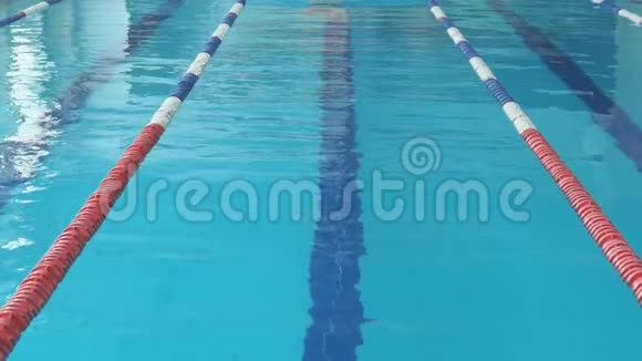 蓝水室内泳池泳泳镜及泳帽蛙泳泳姿的年轻女子视频的预览图