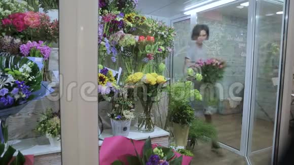年轻女子花店在冰箱里组装了一束花视频的预览图
