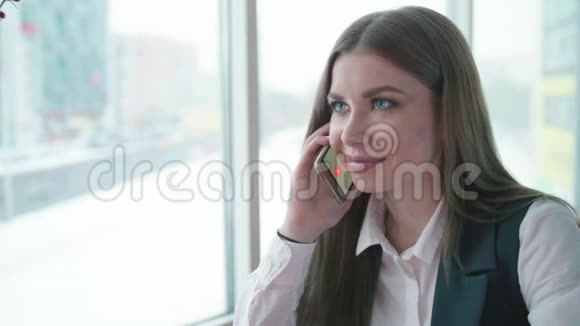 一个女商人坐在咖啡馆里微笑着打电话视频的预览图