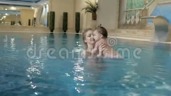 健康的家庭妈妈教女婴在游泳池游泳视频的预览图