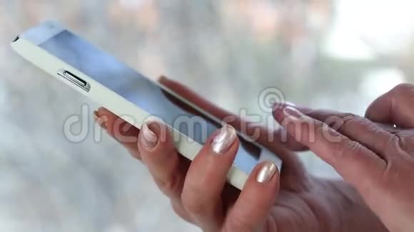 女人拿着白色手机女人在智能手机里看照片视频的预览图