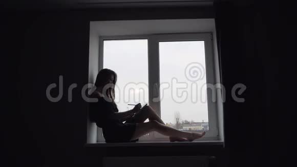 坐在窗台上的迷人女孩剪影视频的预览图