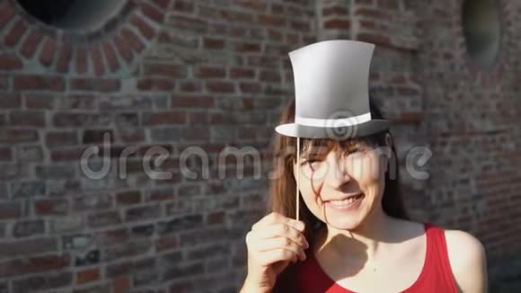 年轻的女人拿着胡子在棍子上站在砖墙旁边视频的预览图