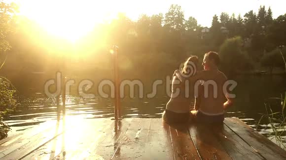 一对浪漫的情侣坐在河边码头一边自拍一边接吻视频的预览图