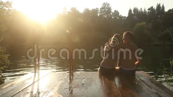 一对浪漫的情侣坐在河边码头一边自拍一边接吻视频的预览图