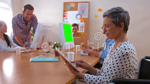 女商人在同事工作时使用平板电脑视频的预览图