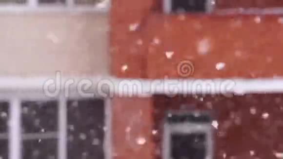 在城里下雪雪花在房子窗户的背景下飞舞视频的预览图