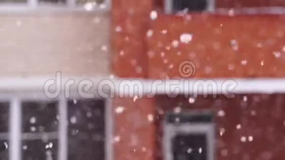 在城里下雪雪花在房子窗户的背景下飞舞视频的预览图