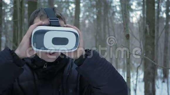 一个人戴着虚拟现实耳机在冬天的雪林他试图触摸虚拟物体一个男人视频的预览图