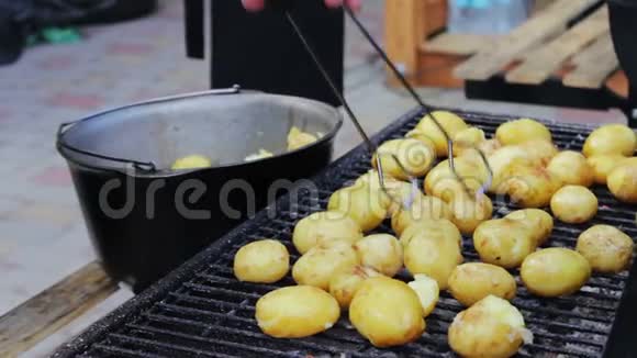 年轻的新鲜土豆在野餐时放在烧烤架上翻过来视频的预览图