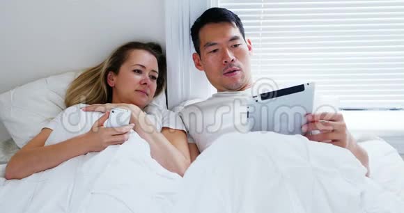 快乐的一对夫妻在床上使用手机数码平板电脑视频的预览图
