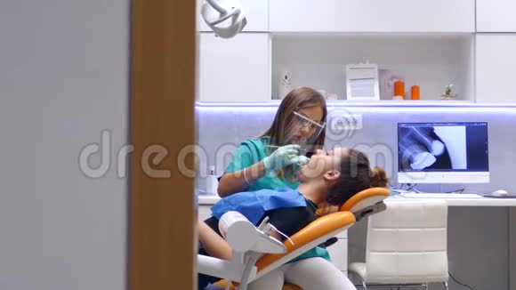 一位年轻的女牙医在牙医办公室里进行了一次移动的拍摄她正在检查和研究病人的牙齿视频的预览图