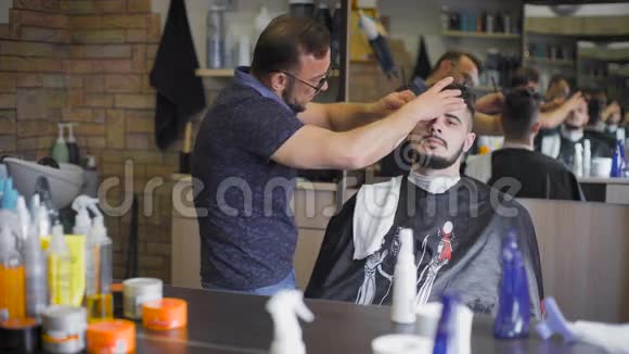 沙龙里的嬉皮士发型专业理发师使用直剃须刀制作胡须趋势形态视频的预览图