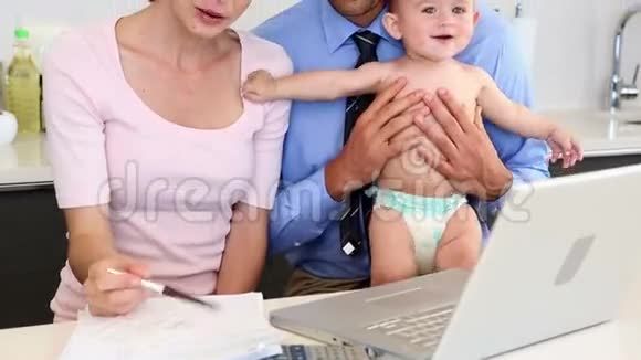 父母用笔记本电脑和他们的小儿子一起计算账单视频的预览图