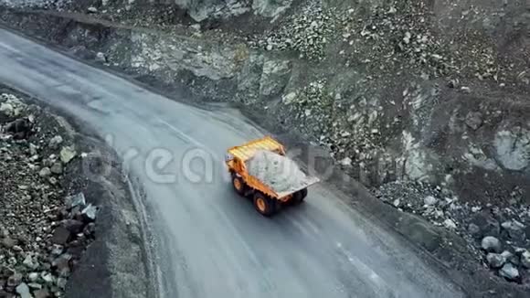 自卸卡车在采石场顶部的景观驾驶橙色自卸卡车与碎石在道路露天坑采矿重型运输视频的预览图