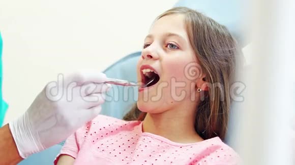 可爱的女孩用嘴镜检查牙齿视频的预览图