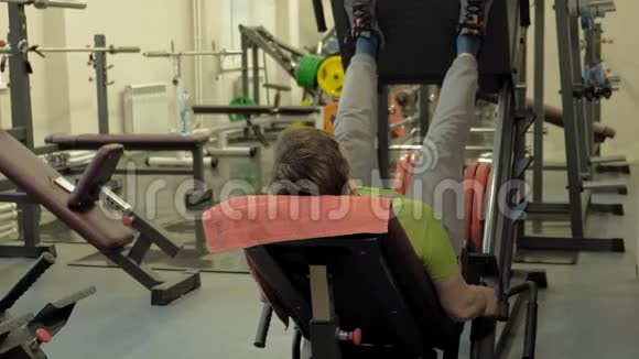 一个超重的男人在健身房里用模拟机做腿部按压健身训练健康生活方式理念视频的预览图