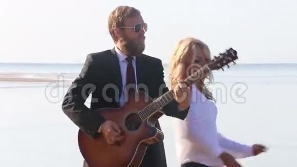 吉他手弹奏金发女郎在海边跳舞视频的预览图