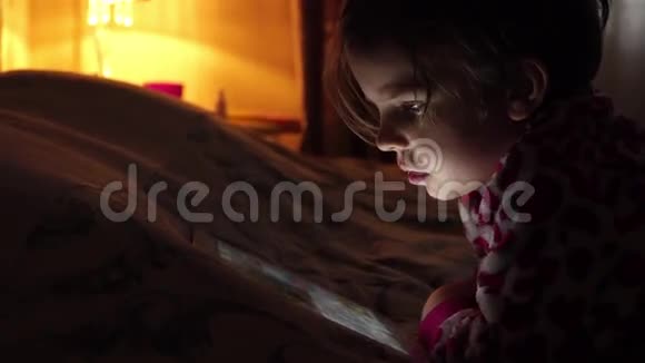 一个在黑暗中看平板电脑的小可爱女孩特写视频的预览图