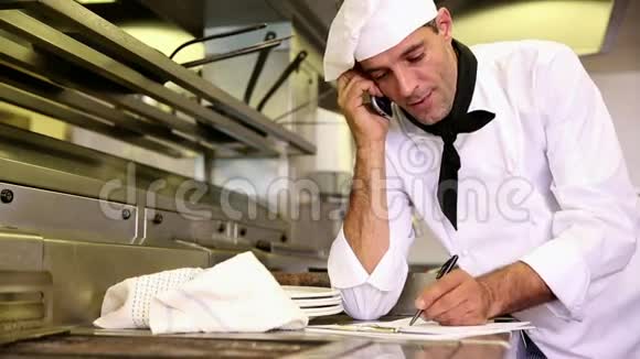 帅哥厨师在电话交谈时在剪贴板上写字视频的预览图