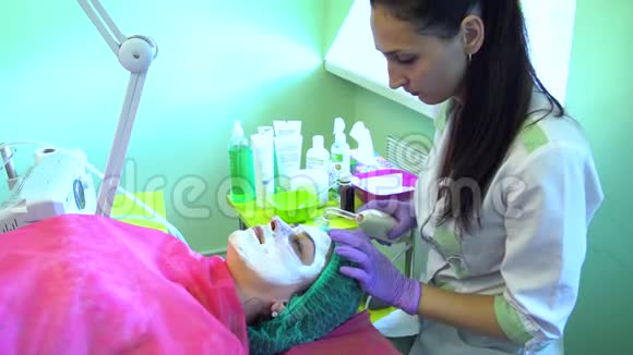一个年轻的女孩在一个接待与美容师面部清洁粒子化视频的预览图
