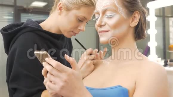 化妆师在模特身上画人体艺术准备拍照会话视频的预览图