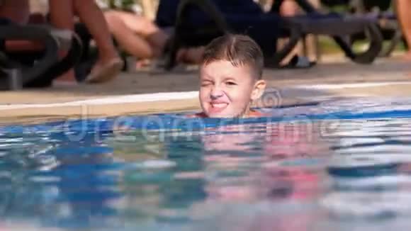 快乐男孩在酒店的游泳池里游泳里面有蓝色的水慢动作视频的预览图