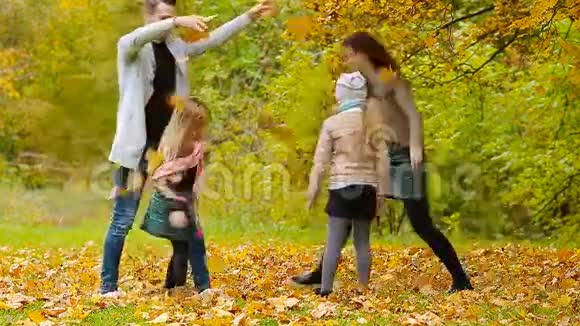 在秋日的户外活动中一个微笑的年轻家庭把树叶扔来扔去视频的预览图
