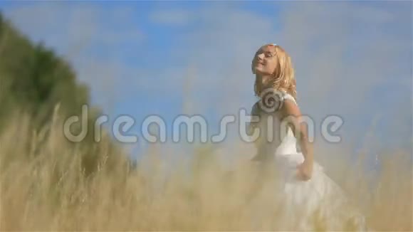 迷人的年轻金发新娘在阳光明媚的夏日在麦田里跳跃和玩耍视频的预览图