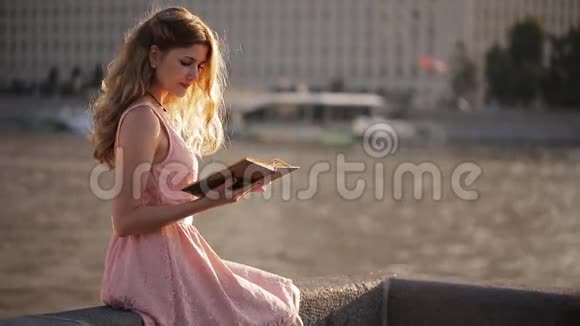 海滨美丽的女孩手里拿着一本书视频的预览图