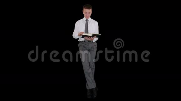 一个年轻的商人看书对着黑色的股票镜头坐着视频的预览图