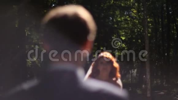 新郎新娘在阳光明媚的公园小巷里接吻视频的预览图