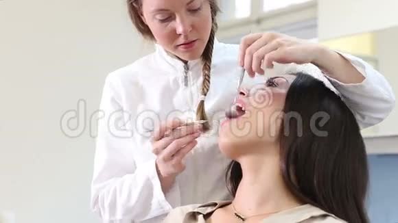 友好的女牙医为美丽的女性病人做检查视频的预览图