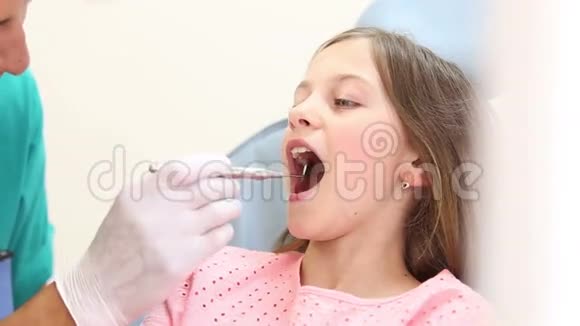 可爱的女孩用嘴镜检查牙齿视频的预览图