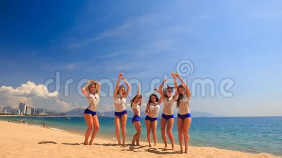穿制服的啦啦队队员在沙滩上表演Tooching篮视频的预览图