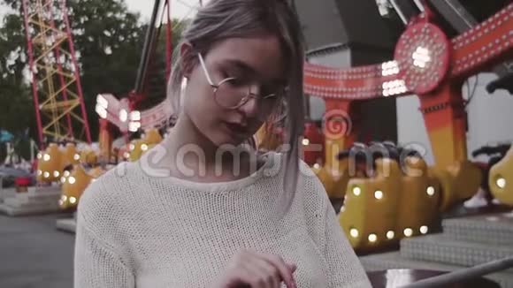 戴眼镜的年轻女孩站在游乐园的秋千附近视频的预览图