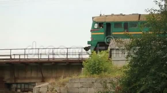 旧的绿色列车在金属铁路桥上行驶背景是灰色的云天视频的预览图
