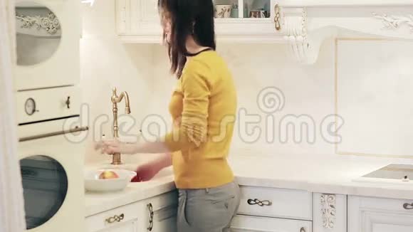 美丽的女孩在厨房里洗苹果视频的预览图