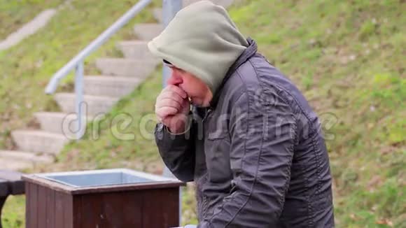 寒冷的人在长凳上咳嗽视频的预览图