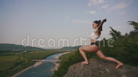 布鲁内特女士健身教练与完美的肌肉身体伸展户外青山景观背景视频的预览图