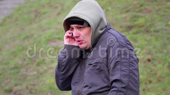在寒冷的天气里男人在户外用手机说话视频的预览图
