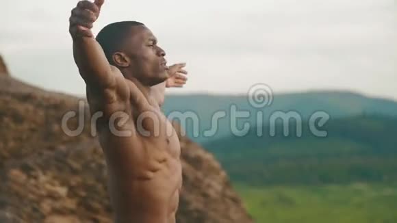 英俊的非裔美国健美运动员户外伸展的侧面山地景观背景视频的预览图