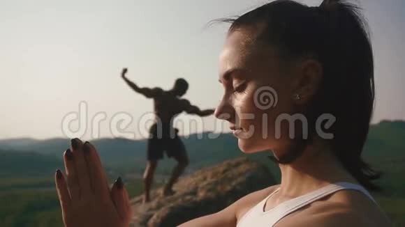 混合种族夫妇白种人妇女和非裔美国健美运动员一起练习瑜伽绿色岩石视频的预览图